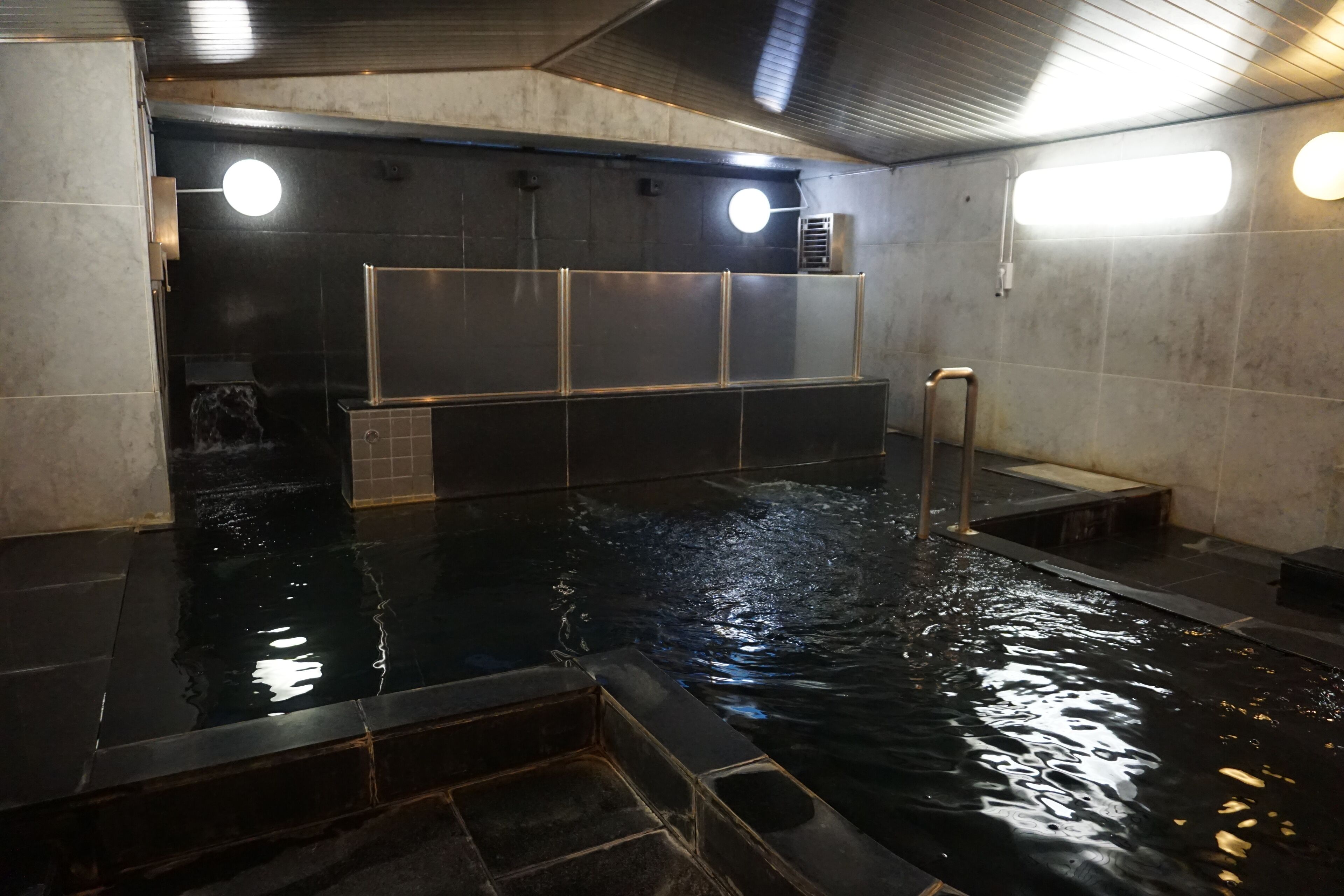 An indoor swimming pool with clear water, tiled walls, and a metal ladder.