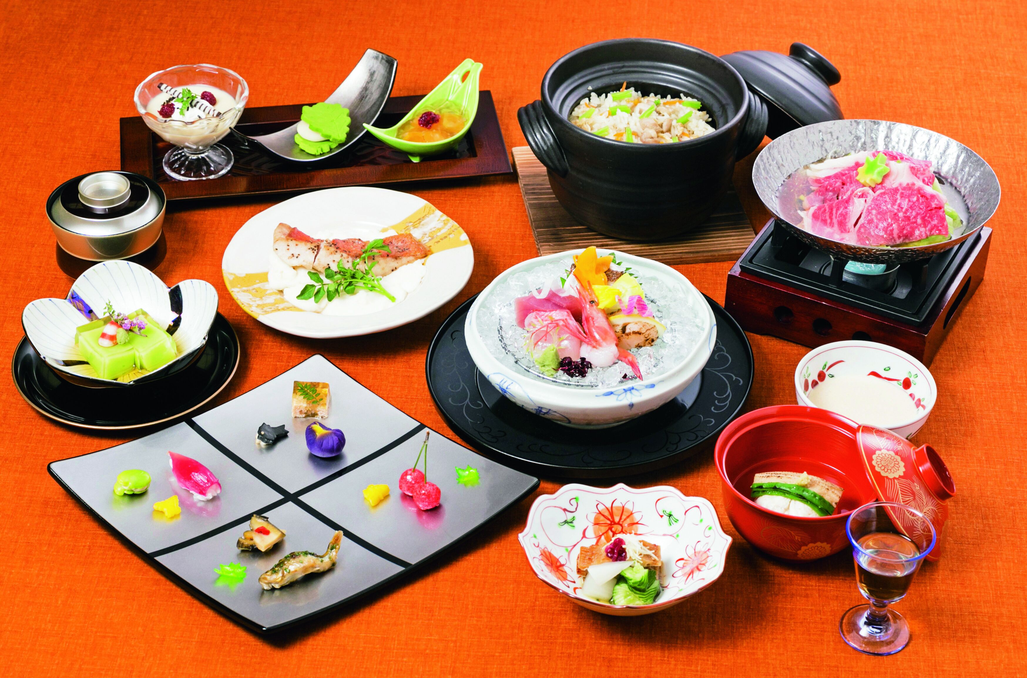 A variety of dishes and a glass of wine on a table.