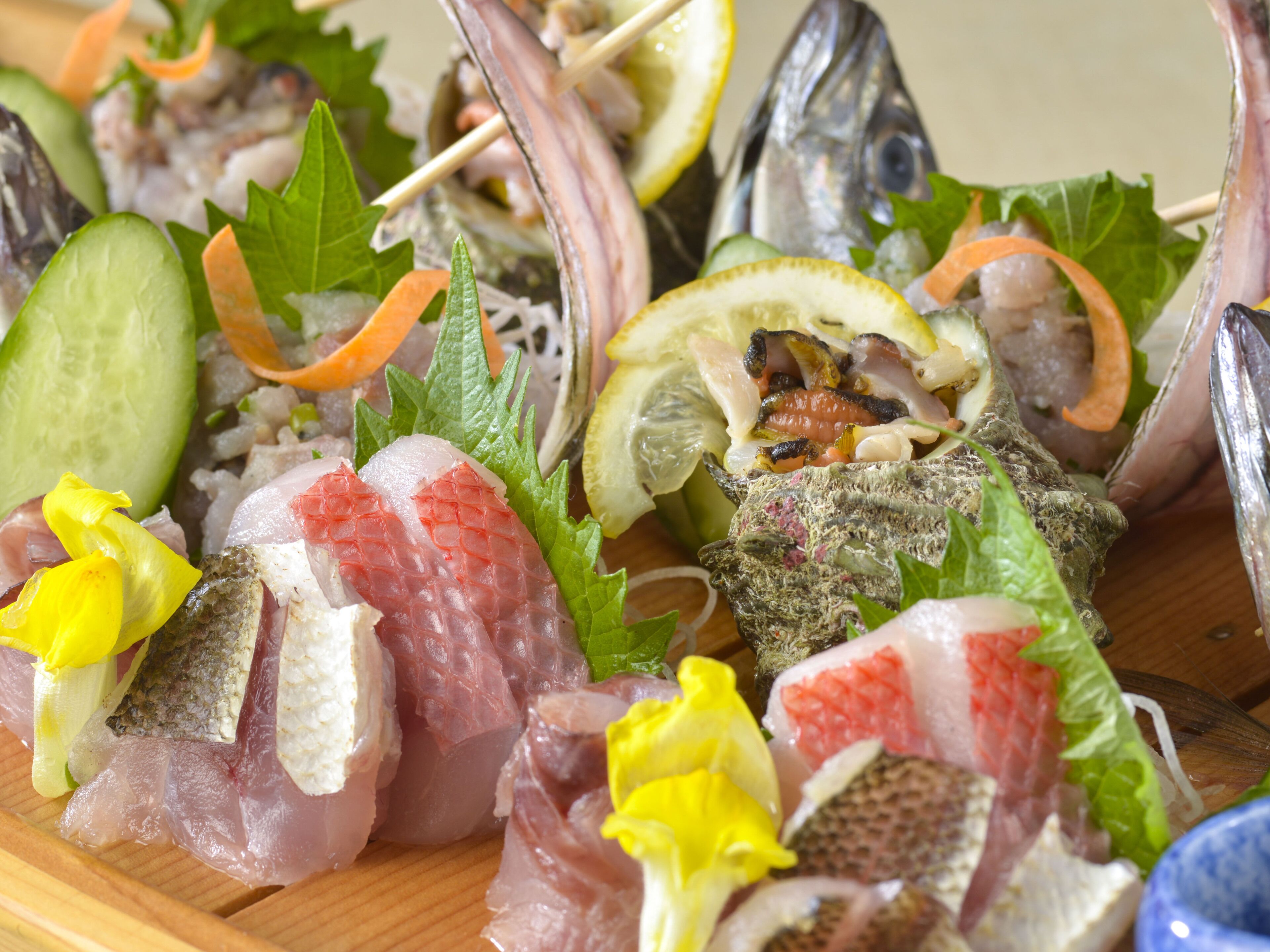 A variety of seafood arranged on a wooden board, including fish, oysters, and vegetables.