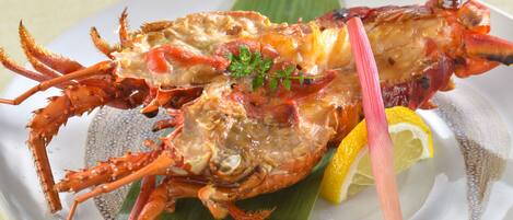 A lobster dish on a plate with lemon and herbs.