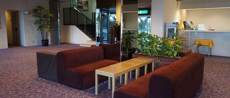 A lobby with seating, a reception desk, and a staircase.