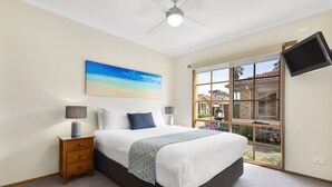 A bedroom with a bed, nightstands, a painting, a TV, and a window with a view. - Riviera Beach Resort (Lakes Entrance)