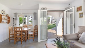 Una sala moderna con sofá, mesa de comedor, sillas y un ventanal corredizo que da a un patio.