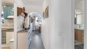 Una cocina moderna con armarios blancos, encimera de madera y un comedor con mesa y sillas.
