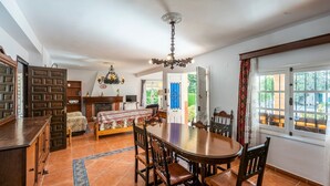 A dining area with a wooden table and chairs, a fireplace, and a view of the outdoors. - El Olivo de Macharaviaya by Ruralidays (Málaga)