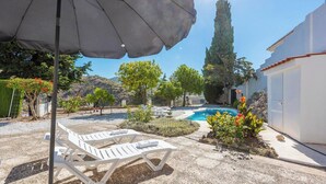 A pool area with lounge chairs, a white building, and a clear sky. - El Olivo de Macharaviaya by Ruralidays (Málaga)