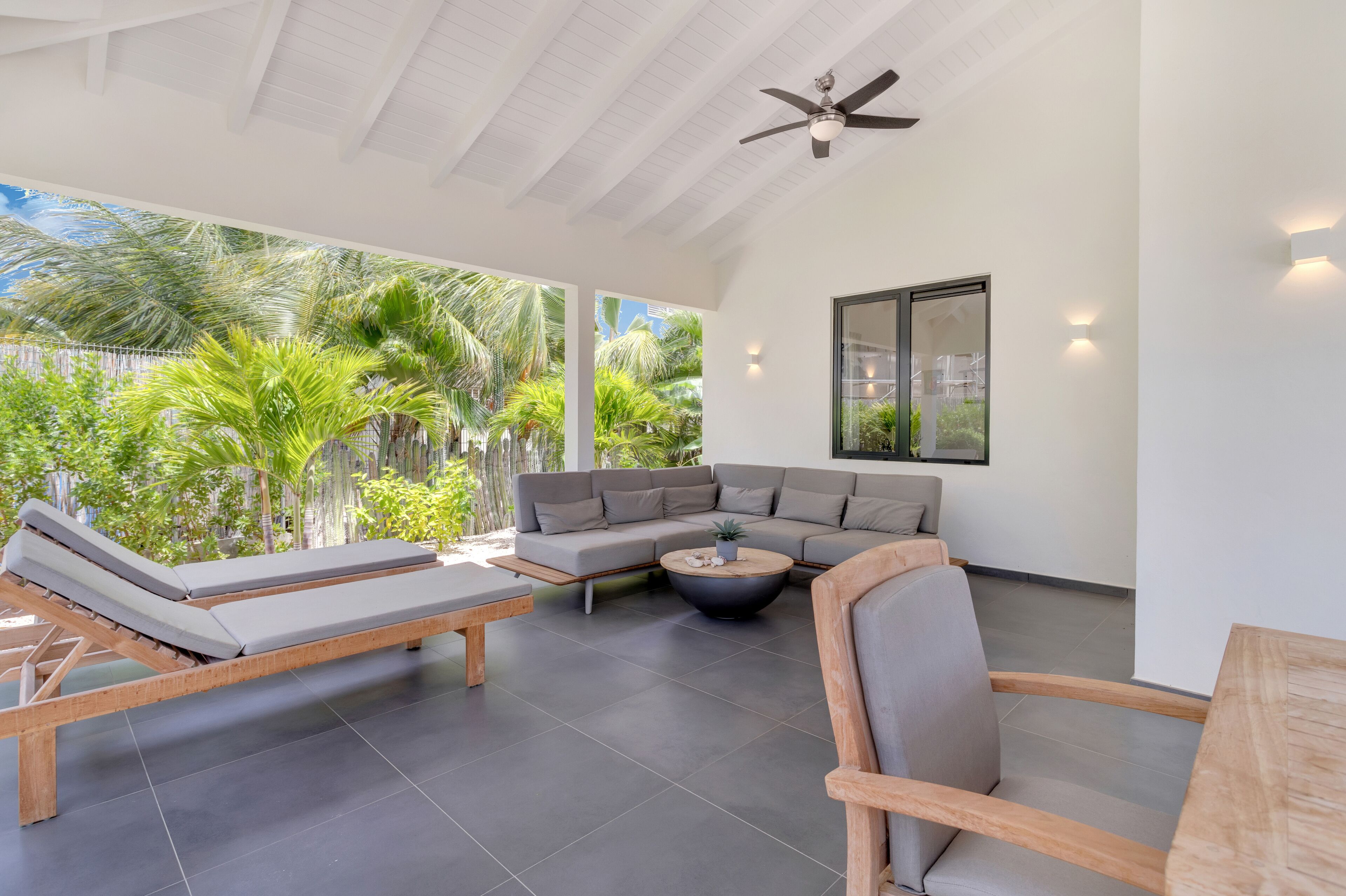 A modern outdoor living area with a sofa, lounge chairs, and a coffee table.