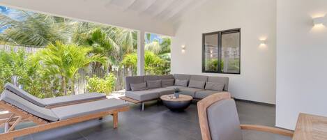 A modern outdoor living area with a sofa, lounge chairs, and a coffee table.