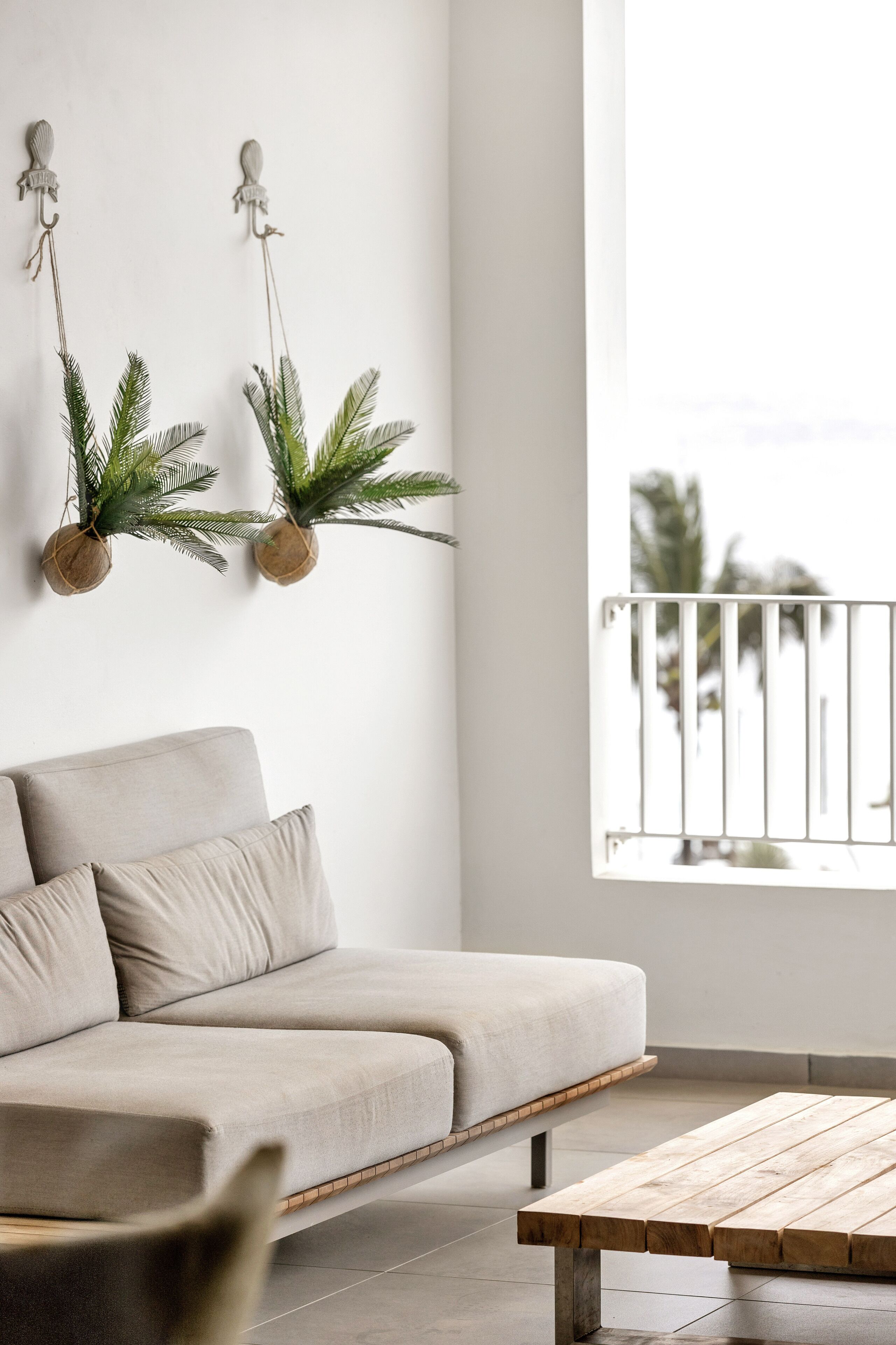 A modern living room with a beige sofa, a wooden coffee table, and two wall-mounted planters with green foliage.