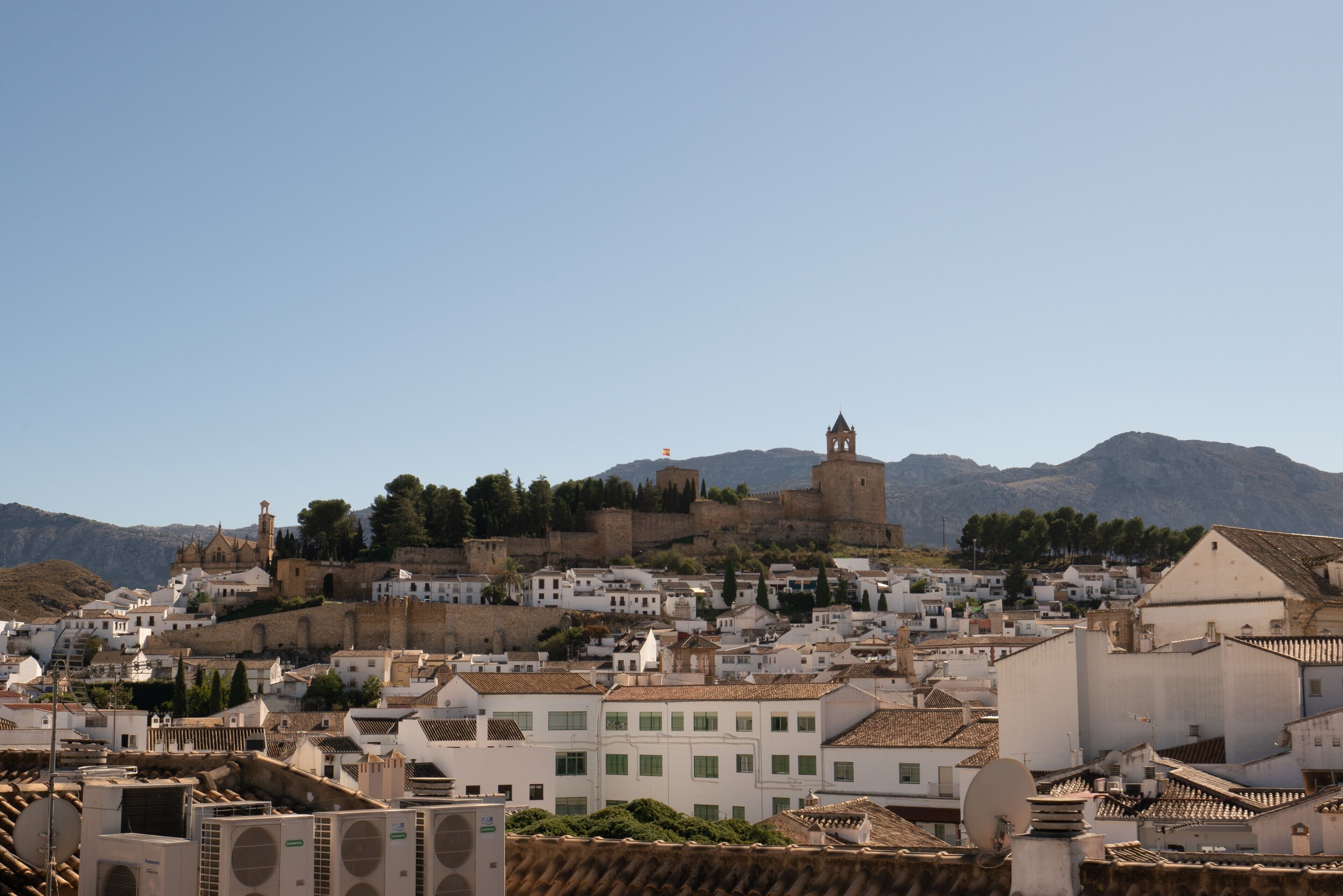 Une ville historique aux bâtiments blancs, avec une église imposante et un ch âteau perché sur une colline.