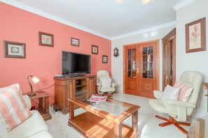 A living room with a television, two armchairs, a coffee table, and a cabinet.