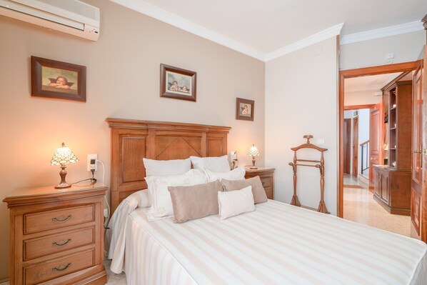 A bedroom with a bed, bedside tables, a dresser, and a mirror.