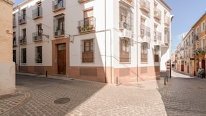 Eine Kopfsteinpflasterstraße mit einem weißen Gebäude, das Balkone und Fenster hat.