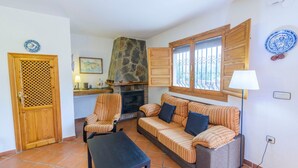 Un salon doté d’une cheminée en pierre, de canapés à rayures, d’une porte en bois et d’une fenêtre offrant une vue agréable.