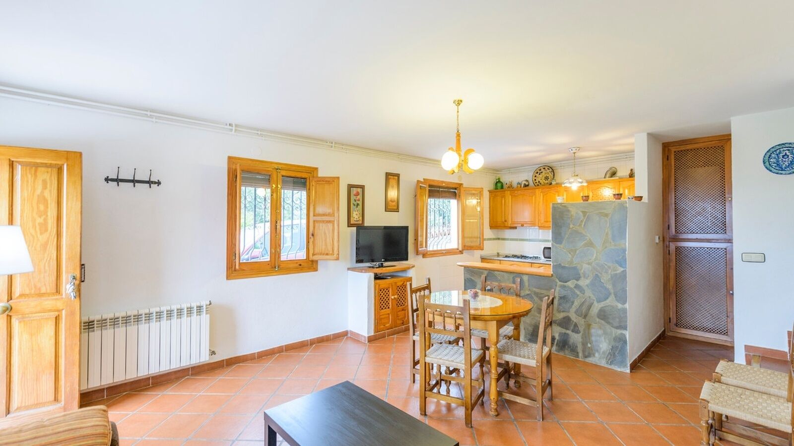 A spacious kitchen with wooden cabinets, a stone island, and a dining area with a round table and chairs.
