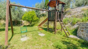 Un ensemble de jeux d’extérieur en bois comprenant une balançoire, un petit toboggan et une échelle.