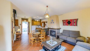 A spacious living area with a fireplace, a dining table with chairs, and a sofa. - Balcón de Válor 5 by Ruralidays (Granada)