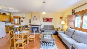 A cozy living room with a fireplace, a dining area, and a kitchen. - Balcón de Válor 5 by Ruralidays (Granada)