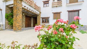 Un edificio con colonne in pietra, porte in legno e un balcone con un parapetto intarsiato.