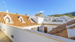 A residential area with terracotta-tiled roofs, white walls, and a clear view of a hillside town. - Ardales 2 pax by Ruralidays (Málaga)
