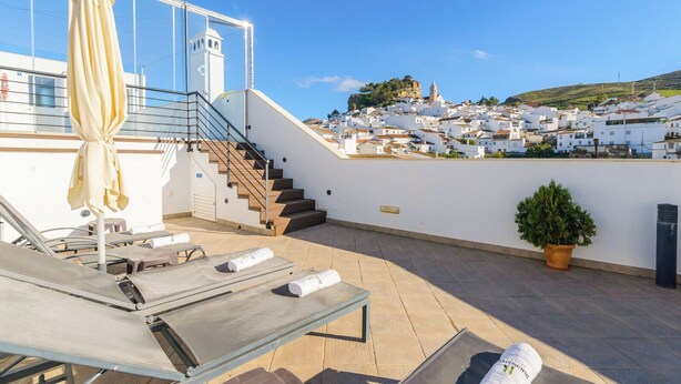A rooftop terrace with lounge chairs, a staircase, and a view of a white-washed town. - Ardales 2 pax by Ruralidays (Málaga)