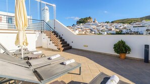 A rooftop terrace with lounge chairs, a staircase, and a view of a white-washed town. - Ardales 2 pax by Ruralidays (Málaga)