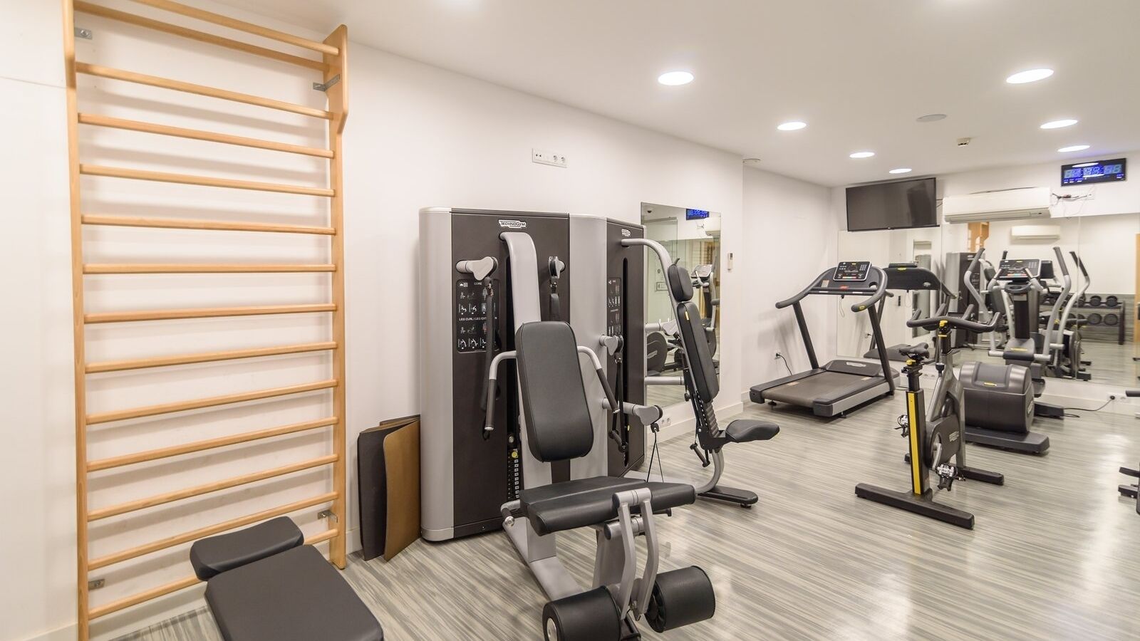 Une salle de sport équipée de divers appareils d’exercice, notamment des tapis de course, des vélos d’appartement et des appareils de musculation.