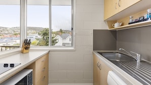 A compact kitchen with a window, a sink, and a countertop with a knife block. - Regent Park (Sandy Bay)