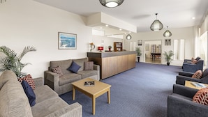 A spacious lobby with a reception desk, seating area, and a view of the dining area. - Regent Park (Sandy Bay)