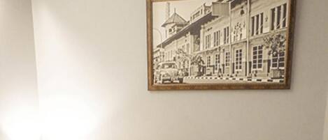 A hotel room with a bed, a nightstand with a lamp, a phone, and a framed picture on the wall.
