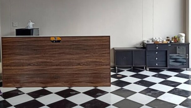 Un hall de hotel con mostrador de recepción, zona de registro y suelo a cuadros.