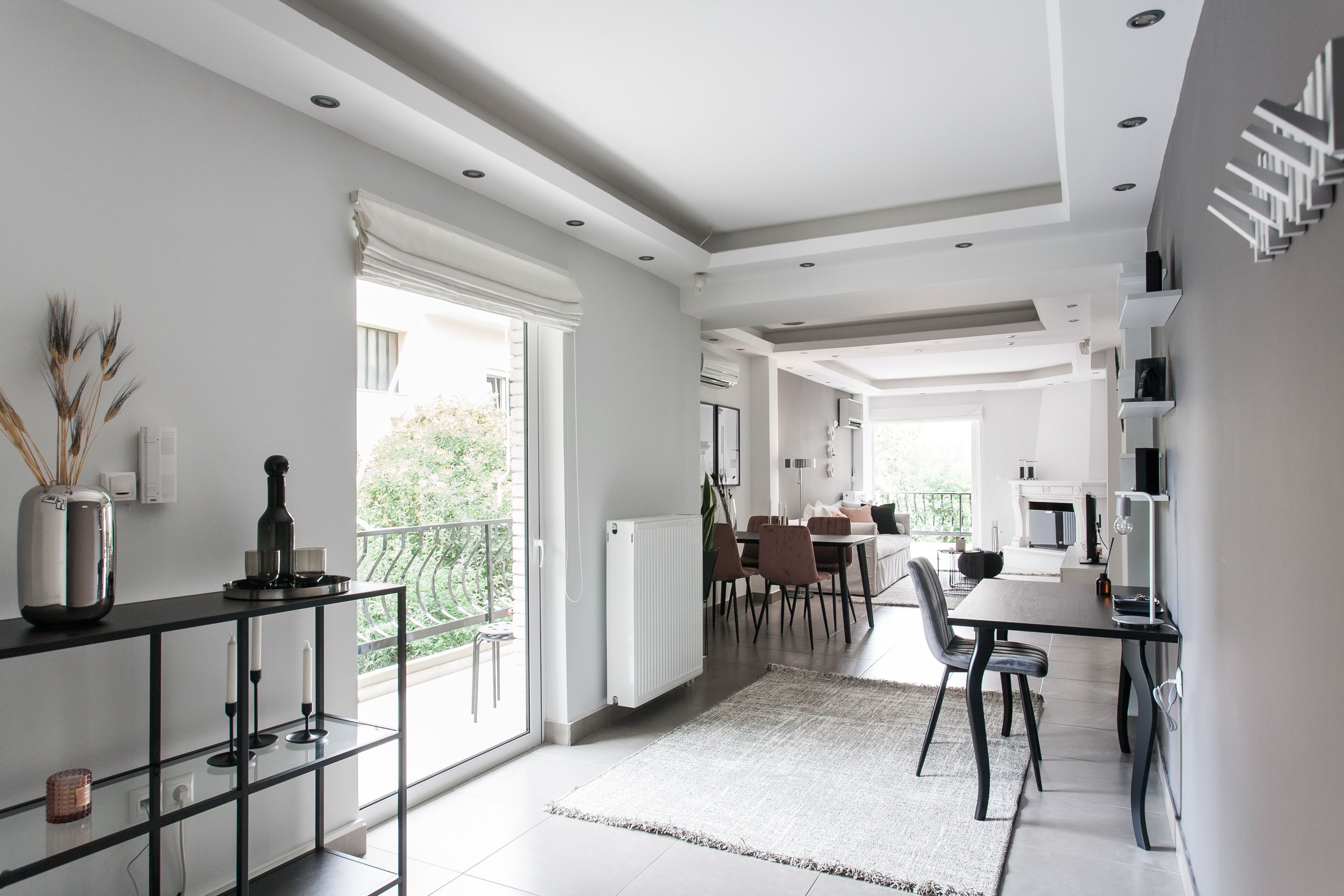 Eine moderne Küche mit Essbereich, inklusive großem Fenster, schwarzem Esstisch und Kücheninsel mit Vase.