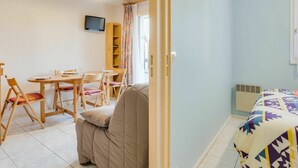 Una habitación con cama, un escritorio con sillas, un televisor y una ventana con cortinas.