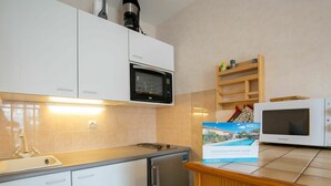 Una cocina moderna con gabinetes blancos, un microondas negro, un microondas Daewoo, un fregadero y una encimera de madera.