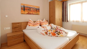 A bedroom with a wooden bed, a nightstand, a wardrobe, and a painting on the wall.