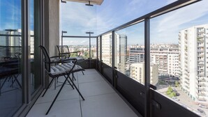 A balcony with a glass door, a chair, and a small table. - Apartamenty InPoint Mogilska Tower (Kraków)