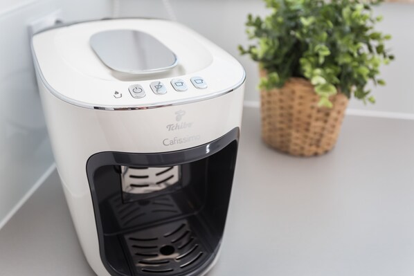 A white coffee maker with a control panel and a water reservoir.
