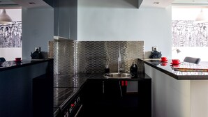 A modern kitchen with a black countertop, a stainless steel sink, and a tiled backsplash. - The Burton Luxury 1BR in Plaka, Athens (Athina)