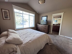 Ein Schlafzimmer mit einem großen Bett, einem Schminktisch, einem Fernseher und einem durchgegangenen Tür erkennbaren Badezimmer.