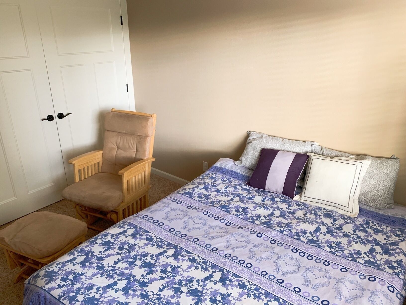 A bedroom with a bed, a wooden chair, and a small stool.