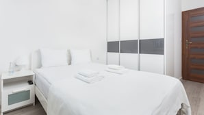 Una habitación de hotel moderna con una cama grande, una mesita de noche con lámpara y una puerta de madera.