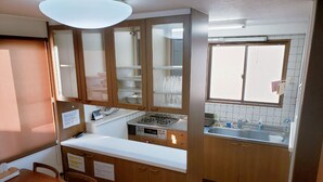 Une cuisine compacte avec des meubles en bois, un plan de travail blanc, une cuisinière à gaz et une fenêtre donnant sur un beau paysage.