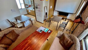 Une chambre d’hôtel moderne avec une table à manger en bois, deux canapés, un téléviseur et un coin cuisine.