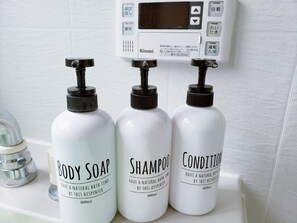 Three bottles of body soap, shampoo, and conditioner on a bathroom counter.
