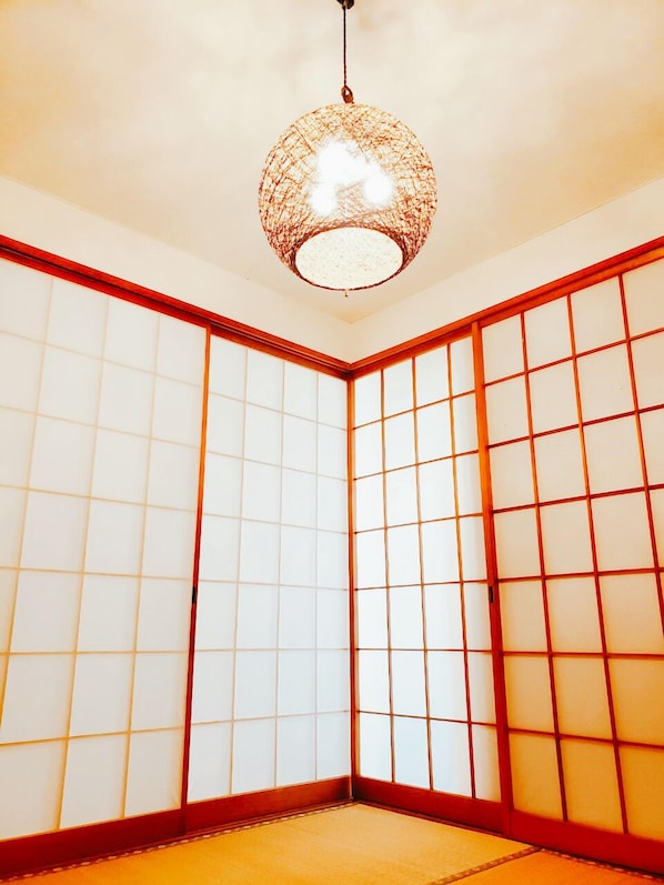 A traditional Japanese room with tatami flooring, shoji screens, and a hanging paper lantern.