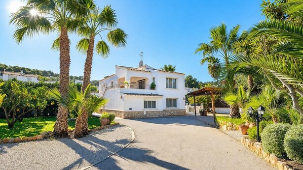 A white villa with a stone facade, a balcony, and a paved driveway. - Large and comfortable villa in Moraira, Costa Blanca, Spain  with heated pool for 12 persons (Moraira)