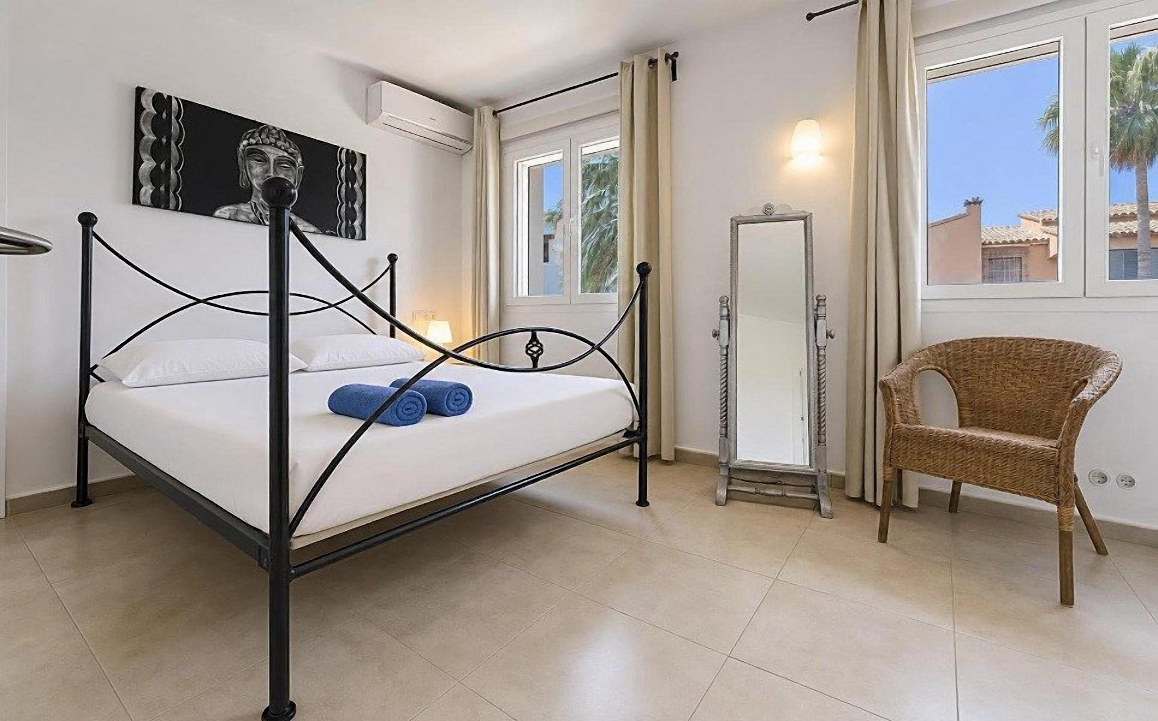 Quarto com cama, cadeira, espelho e janela.