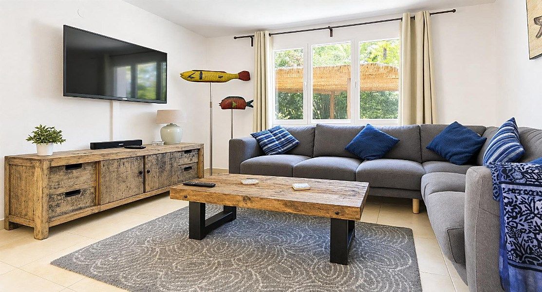 Una sala de estar con sofá, mesa de centro, televisor y peces decorativos en la pared.