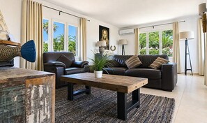 Un salon moderne avec un canapé en cuir, une table basse en bois et une plante en pot.