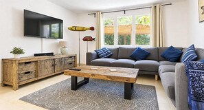 Un salon avec un canapé, une table basse, un téléviseur et des poissons décoratifs accrochés au mur.